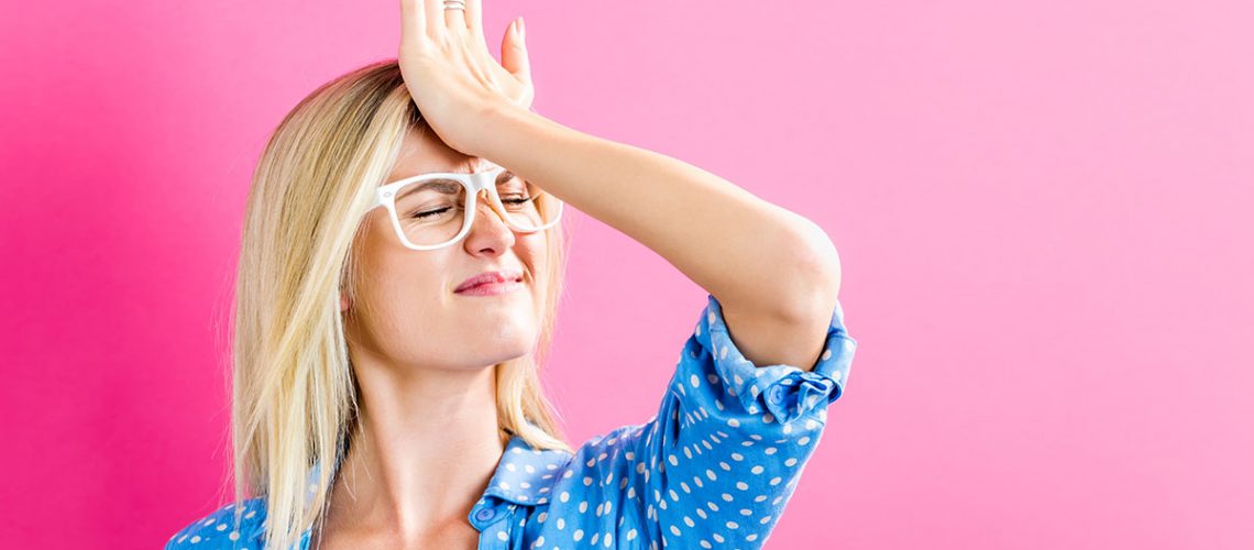 Young woman making a mistake on a pink background