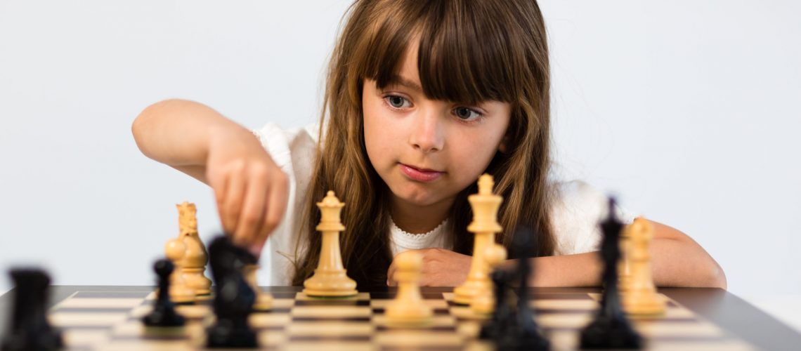 Young caucasian girl with long hair playing a game of chess.